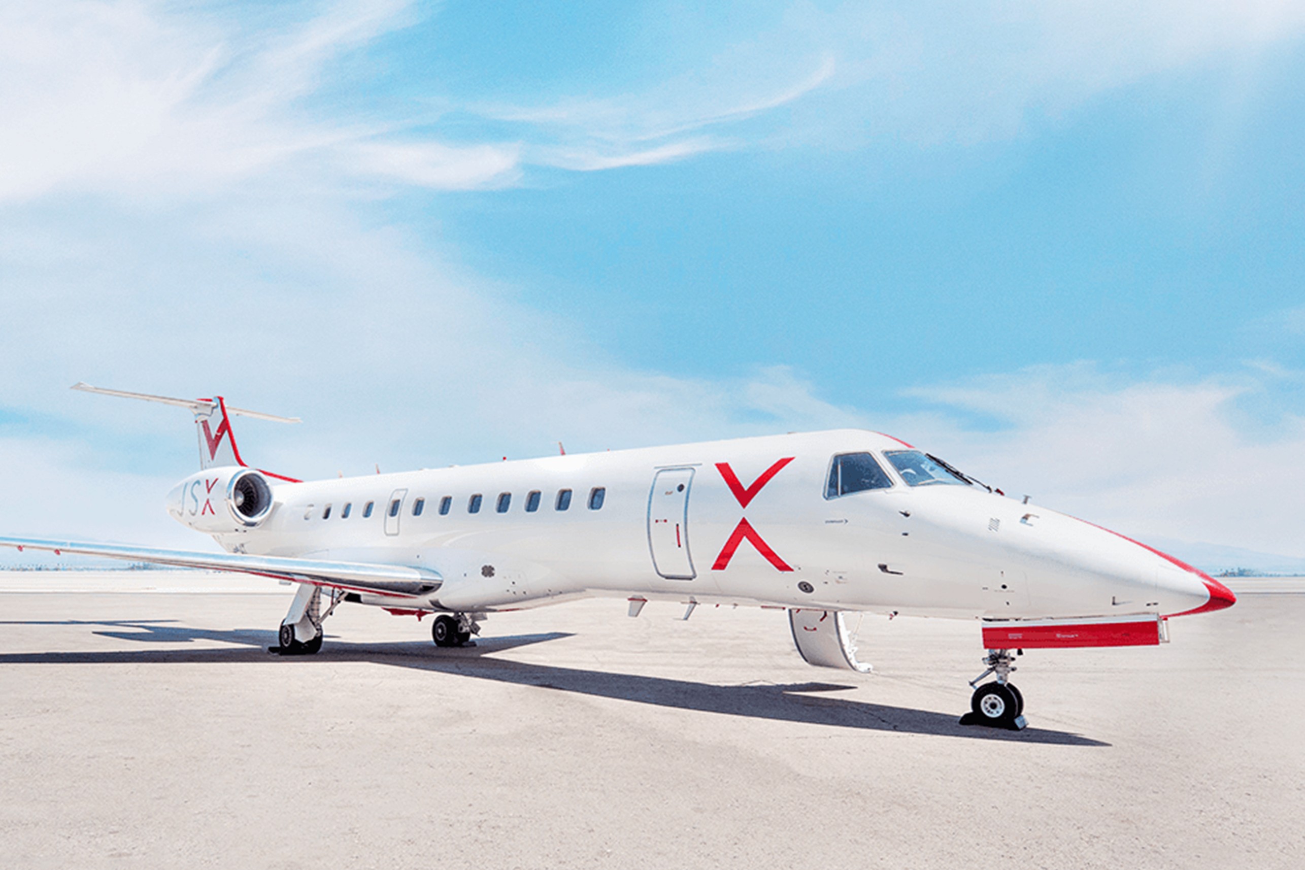 JSX 'hop-on jet service' Embraer regional jet parked on the tarmac, showcasing the modern white livery with a red X logo